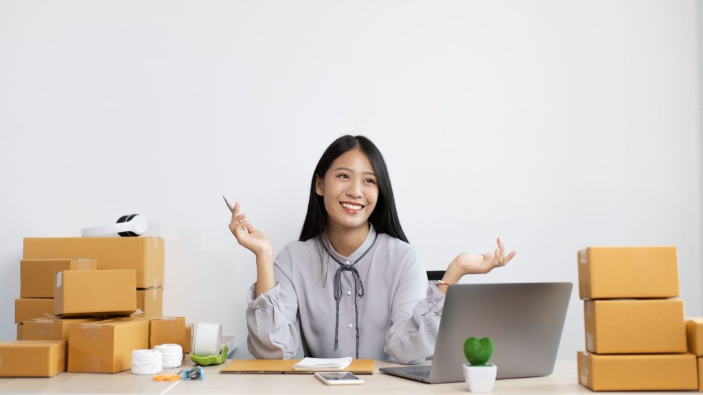 business owner sitting at laptop with product boxes around her