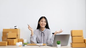 business owner sitting at laptop with product boxes around her