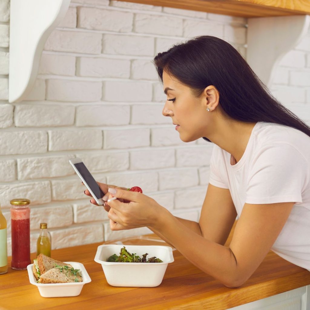 person scrolling on phone while eating lunch